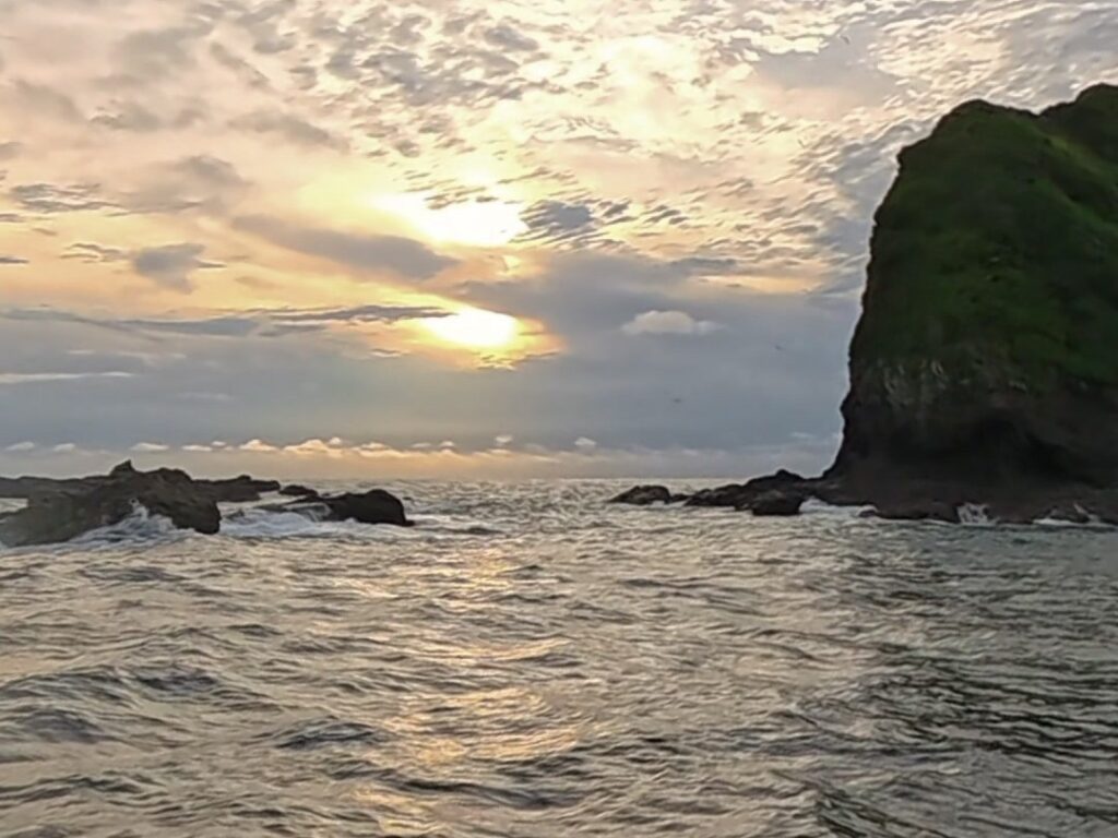 Atardecer sobre el mar con un islote cubierto de selva
