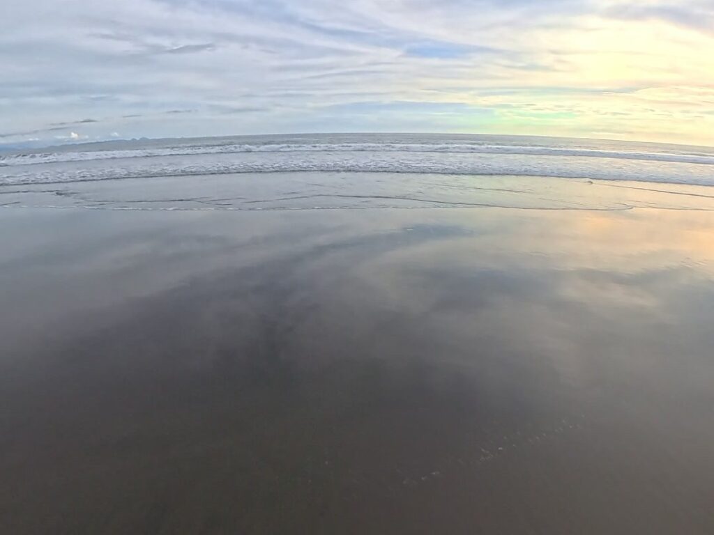 Playa de arena oscura vacía al amanecer